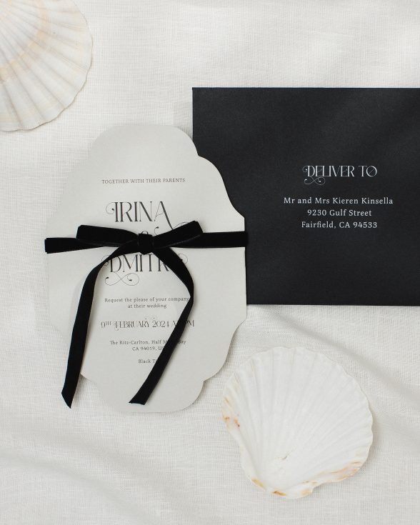 Vintage inspired cut to shape wedding invitation in grey with ornate font and black velvet bow. black envelope