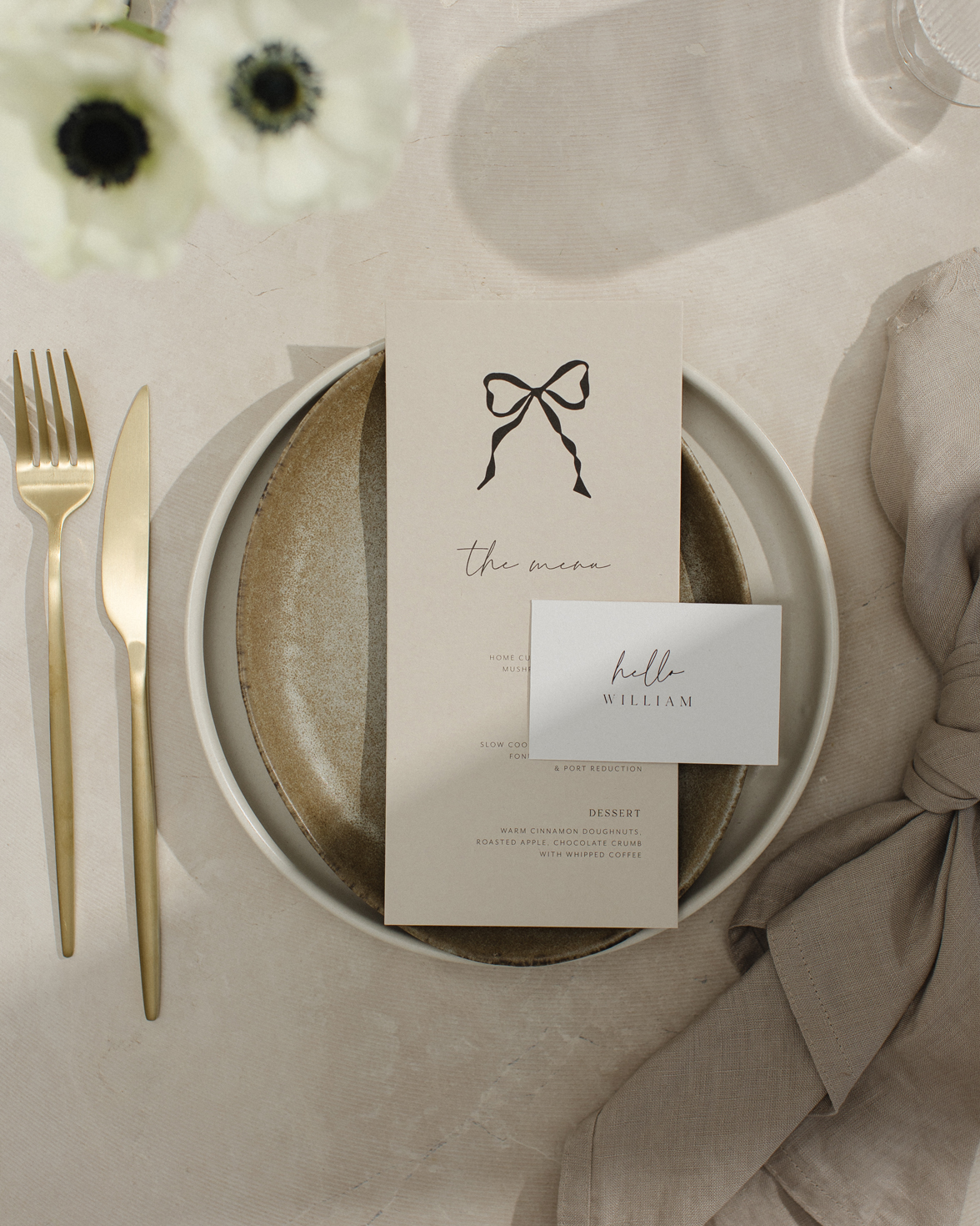 Wedding menu in stone colour with black hand drawn bow. White flat rectangle place card with script font