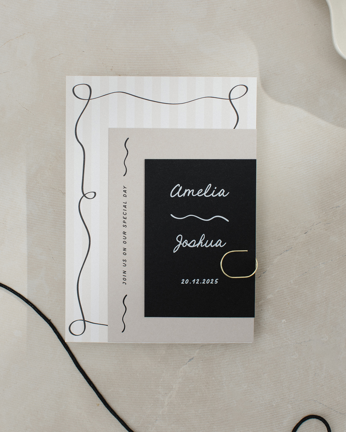 Wedding stationery bundle with gold clip. Tonal stripe wedding invitation with squiggly border and hand drawn font. Black RSVP card with white ink and QR code. Stone coloured details card with squiggly line