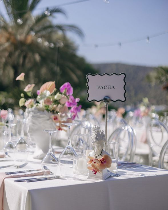 Wedding table name white with black border and wavy scalloped edge. Pink flowers on table